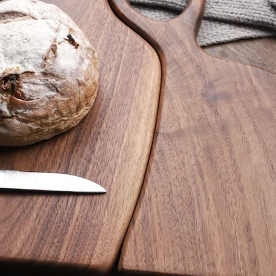 Wooden cutting board with a loaf of bread and knife on a wooden surface