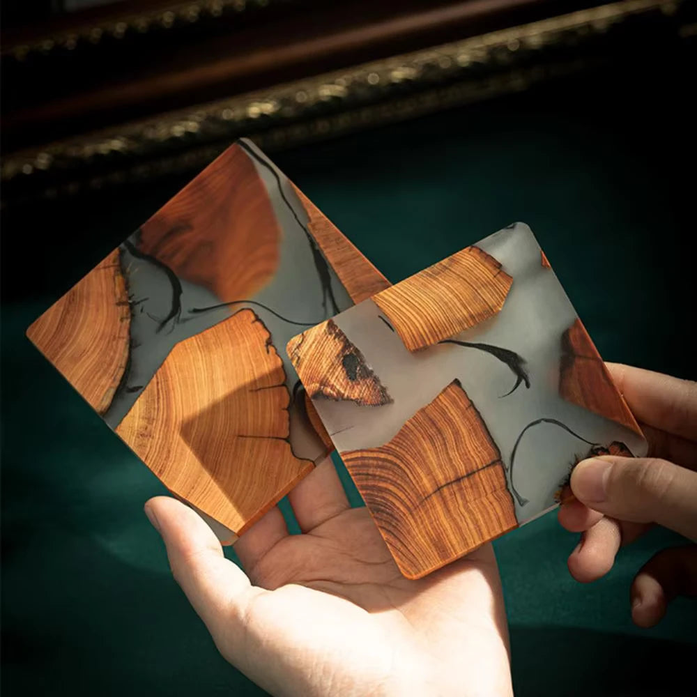 Wooden coasters with a marble-like finish held by a hand against a dark background