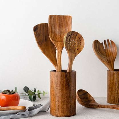Set of wooden kitchen utensils in a holder on a light background