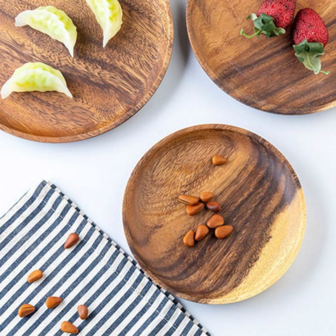 Three wooden plates with food items on a white surface