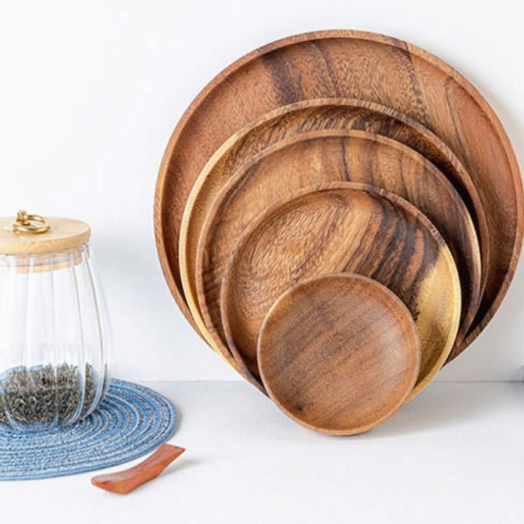 Set of wooden plates on a white surface with a glass jar and blue mat in the background.
