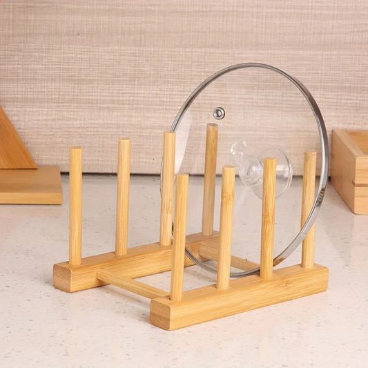 Wooden dish rack holding a glass lid on a neutral background
