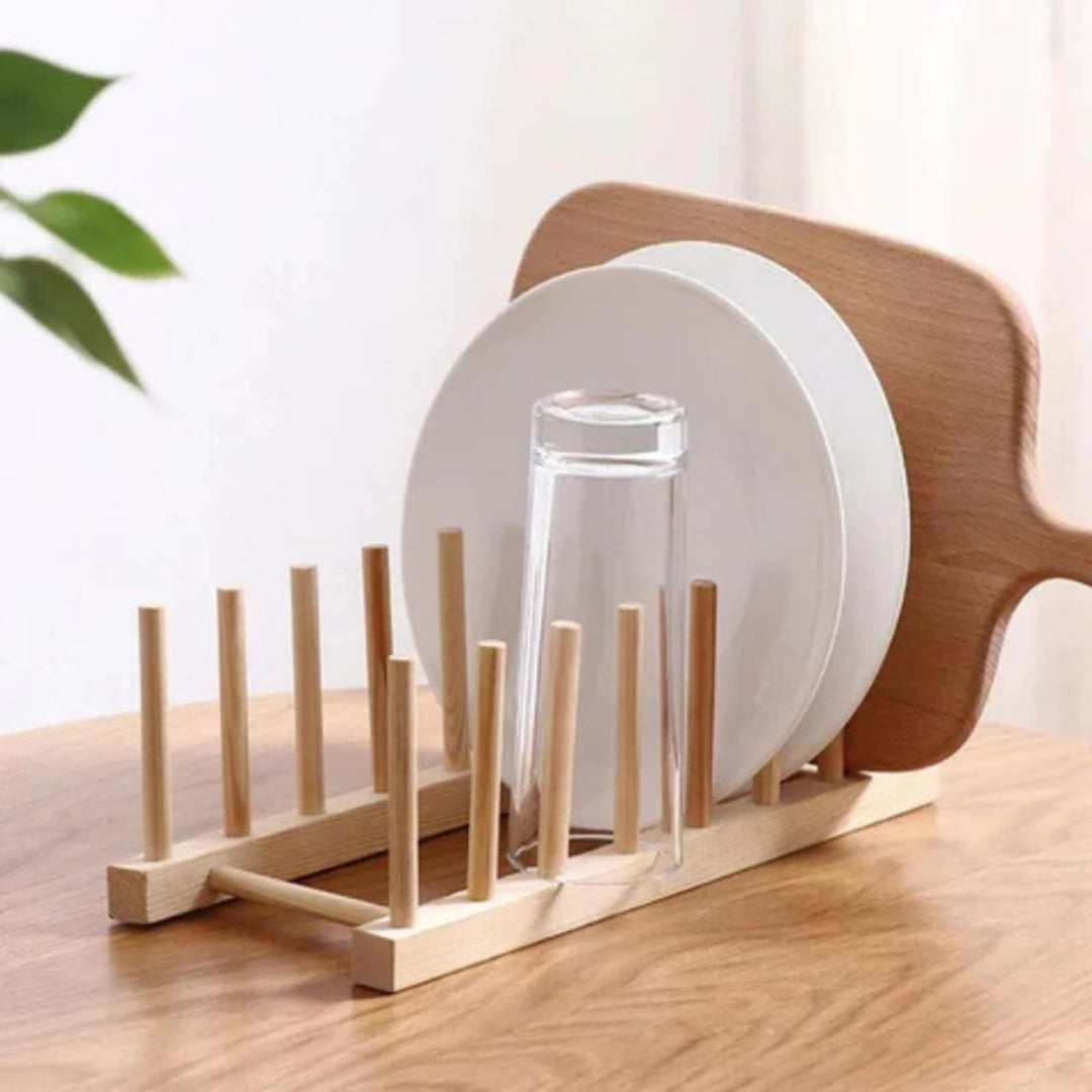 Wooden dish drying rack with plates and a glass on a wooden surface.