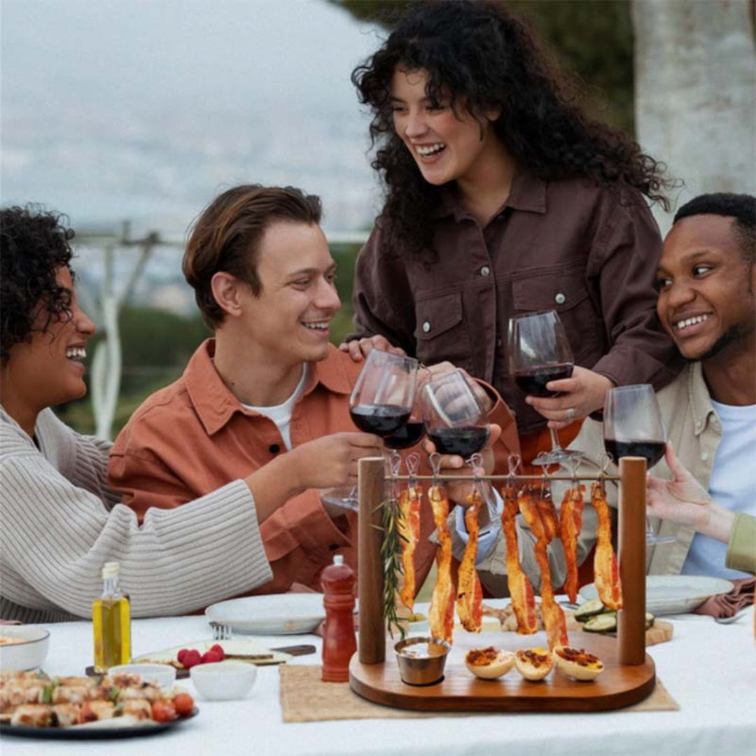 Group of people enjoying a meal and drinks outdoors with a wooden appetizer tray.