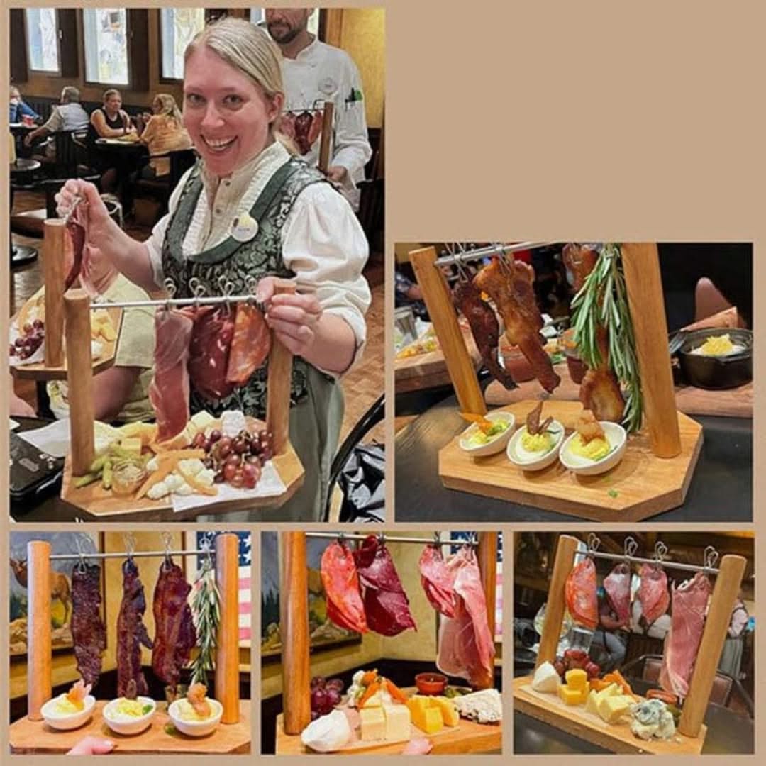 Woman holding a wooden board with cured meats and cheeses in a restaurant setting.