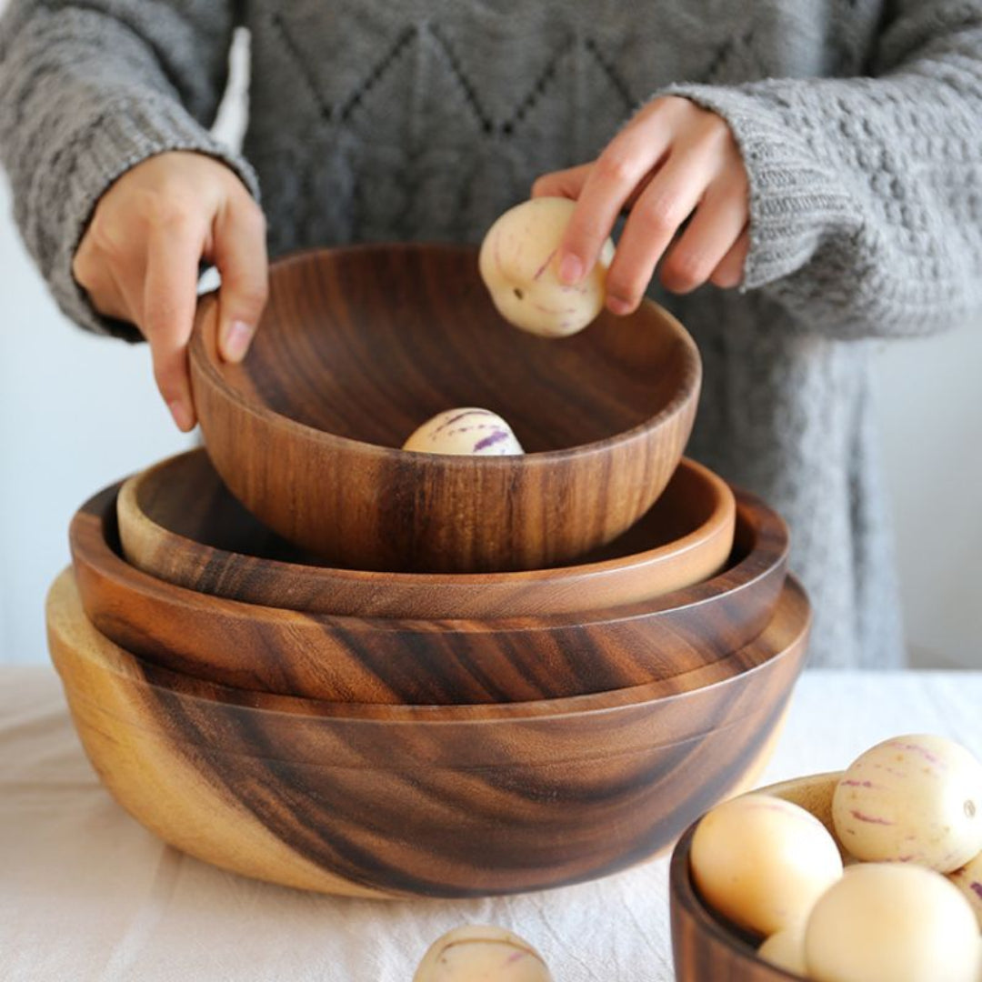 Stack of wooden bowls with a person holding a small object.