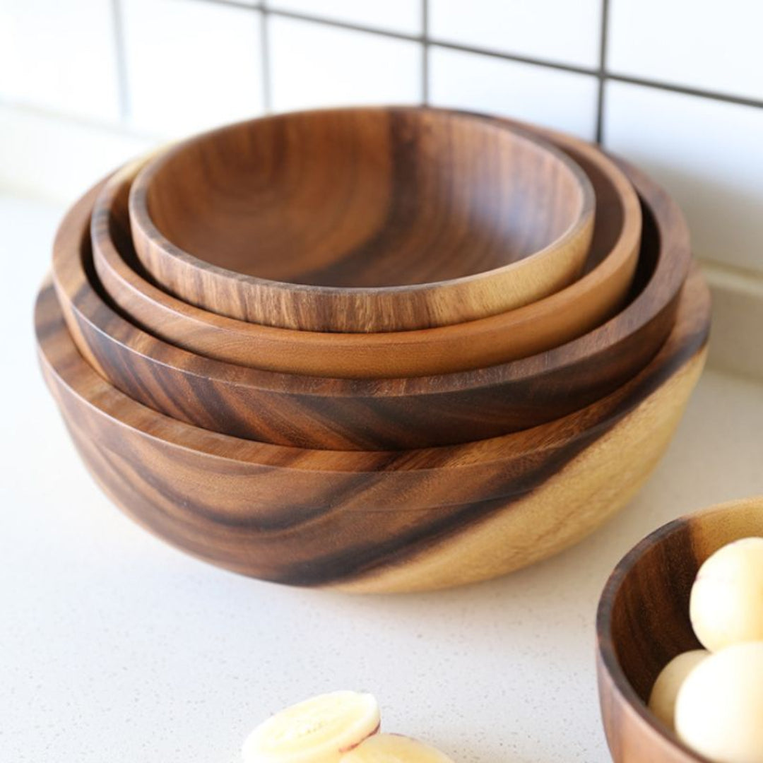 Set of wooden bowls stacked on a white surface with a tiled wall background