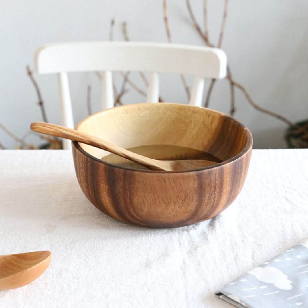 Wooden bowl with a wooden spoon on a white surface with a blurred background