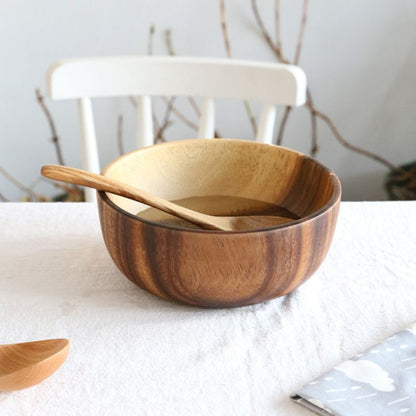 Wooden bowl with a wooden spoon on a white surface with a blurred background