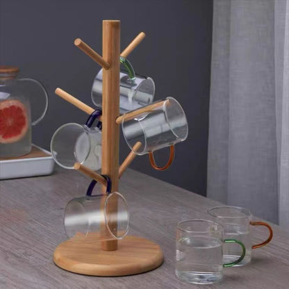 Wooden mug tree with hanging clear glasses on a wooden surface.