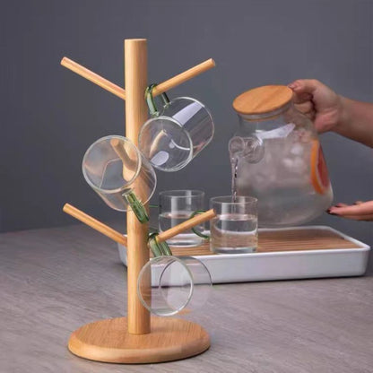 Wooden mug rack with glasses and a glass jar on a gray surface.