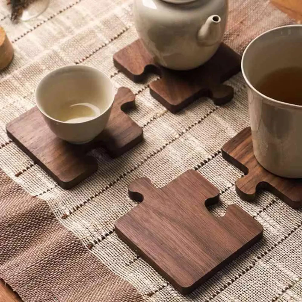 Wooden coasters on a textured surface with tea cups and a teapot.