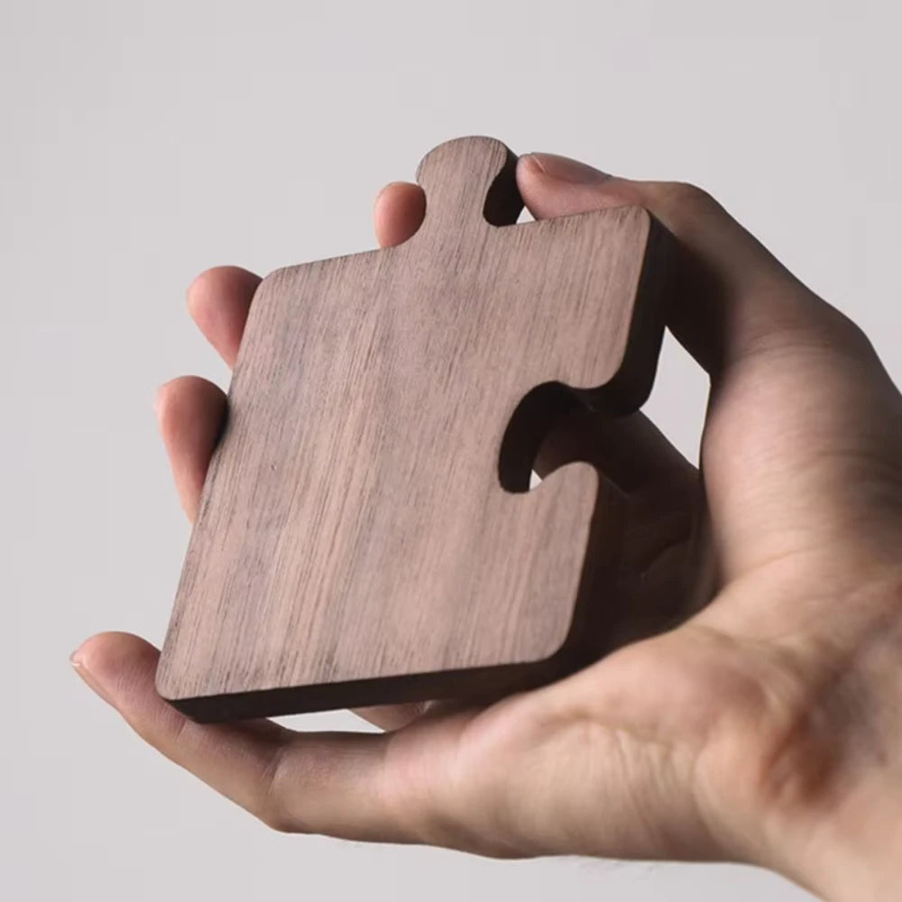Wooden puzzle piece held in a hand against a plain background