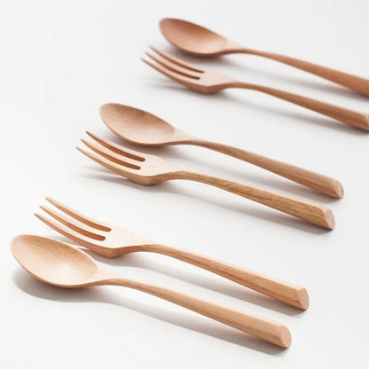 Set of wooden spoons and forks on a light background