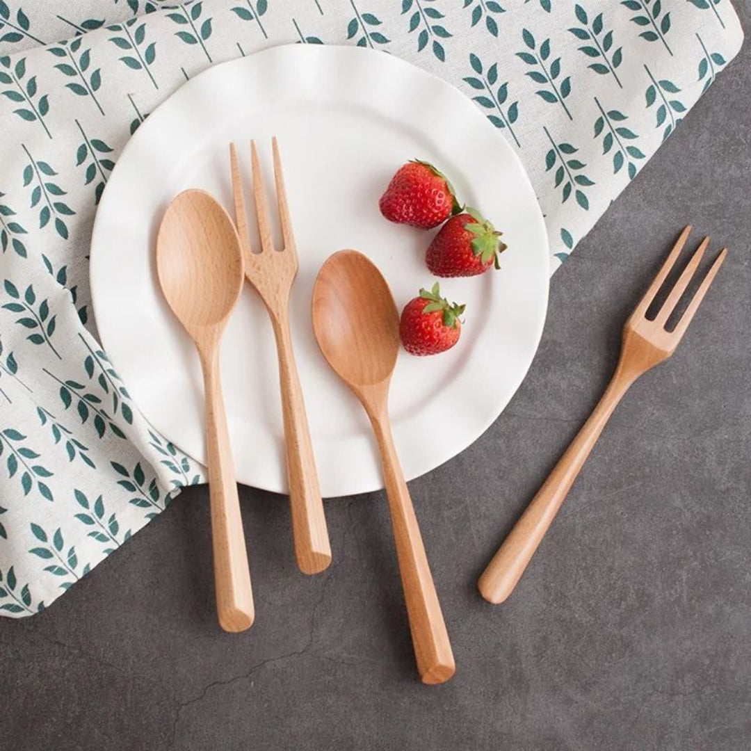Wooden cutlery set with strawberries on a white plate against a patterned cloth background