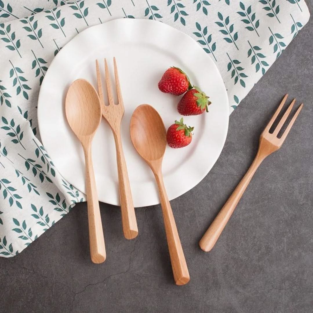 Wooden cutlery set with strawberries on a white plate against a patterned cloth background