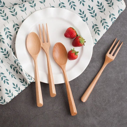 Wooden cutlery set with strawberries on a white plate against a patterned cloth background