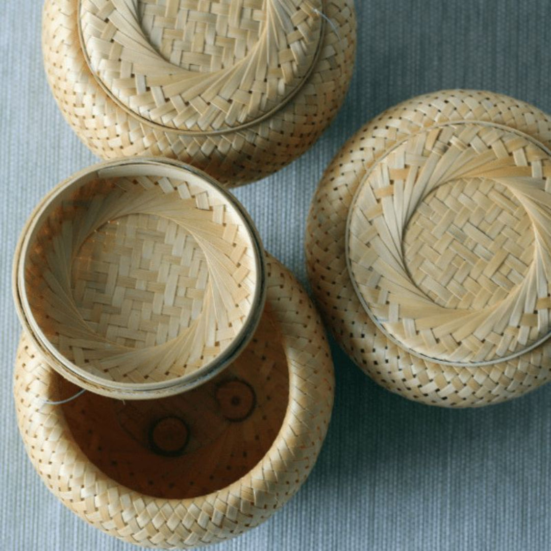 Three woven baskets with lids on a textured surface