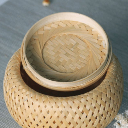 Woven bamboo container with lid on a textured surface