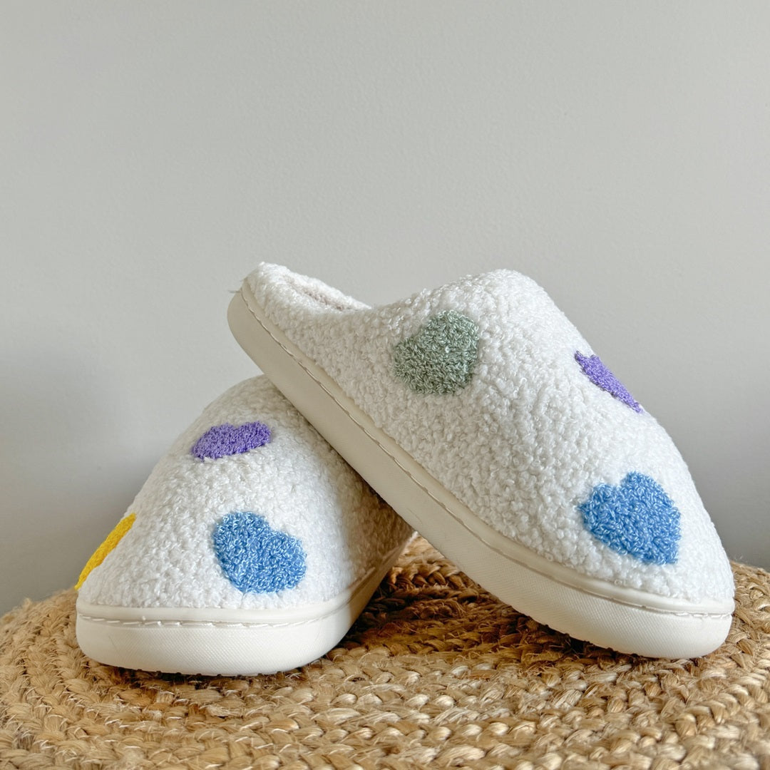 White slippers with colorful polka dots on a textured surface
