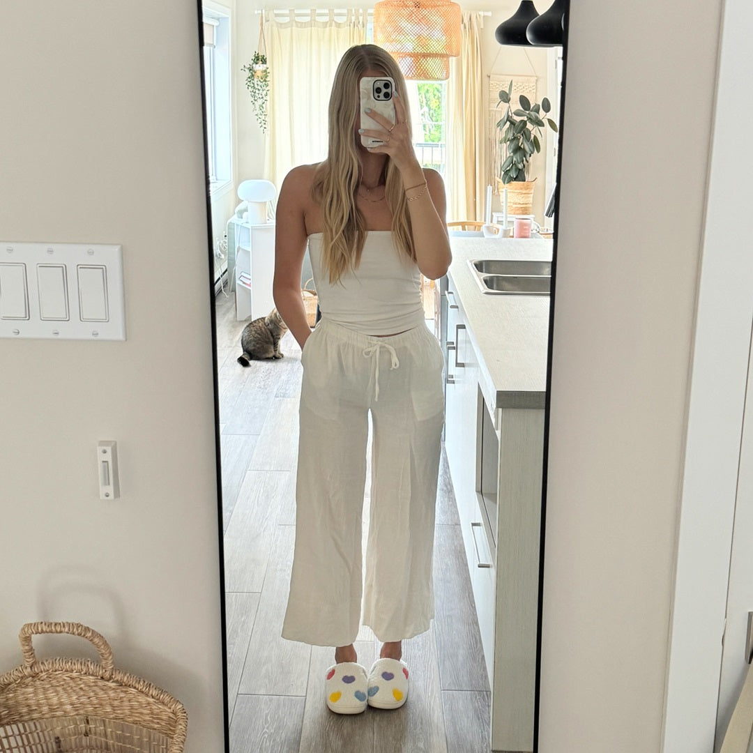 Person taking a mirror selfie wearing a white outfit in a kitchen.
