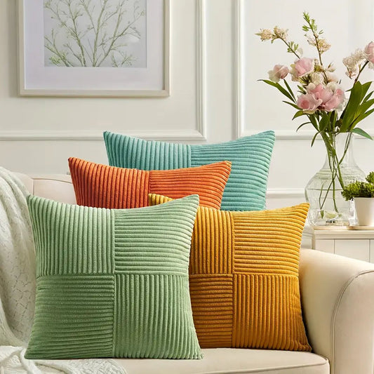 Colorful textured pillows on a sofa with a vase of flowers in the background
